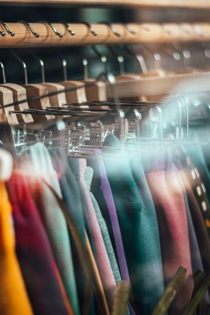 services-02 Vibrant clothing lined up on hangers behind a glass window, showcasing a modern retail store.