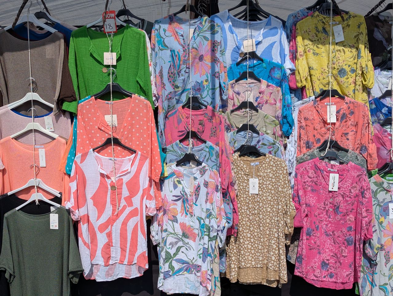 services-03 A vibrant display of summer blouses in various patterns, showcased at a market in Knaresborough, England.