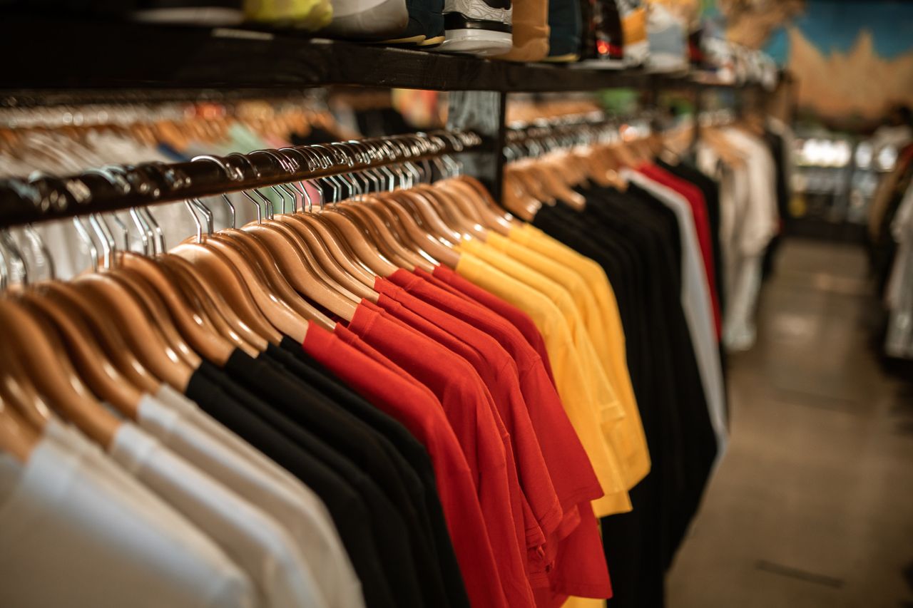 gallery-6 Clothing store display with shirts hanging neatly on a rack indoors.